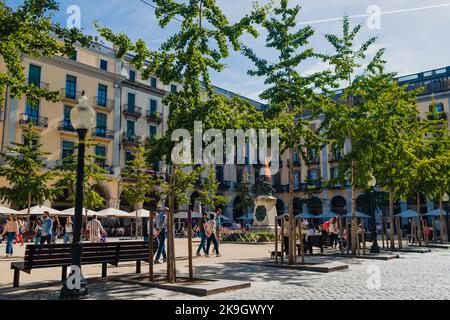 Girona, Spagna il 22 ottobre 2022: Piazza dell'Indipendenza nel centro della città di Girona in una giornata di sole estate con persone, caffè e cielo blu. Tradizione Foto Stock