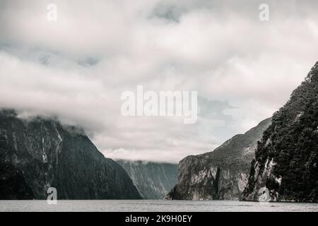 grande lago con acque calme vicino alle imponenti alte montagne solitarie e calme con un sacco di verde e molti alberi, milford sound, nuova zelanda Foto Stock