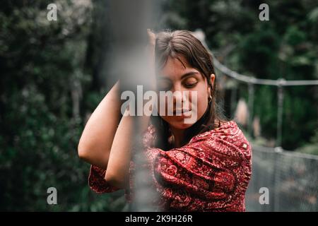 ragazza caucasica con occhi blu capelli castani e orecchini nel suo orecchio meditando guardando giù sul ponte sospeso in isola di donut, nuova zelanda Foto Stock