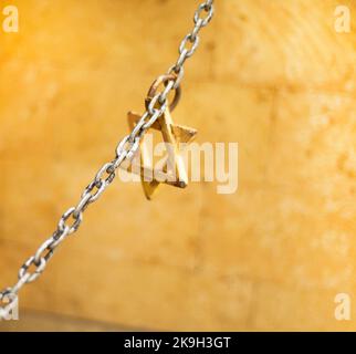 Stella di David su una catena metallica. Sfondo giallo. Copia spazio per il testo. Cultura ebraica. Parete di lacrime. Foto Stock