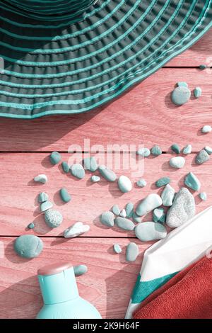 Immagine verticale con cappello turchese, creme e ciottoli sulla terrazza. Tema delle vacanze estive Foto Stock
