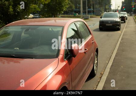 Auto rossa nel parcheggio. L'auto è sul lato della strada. Trasporto in città in estate. Vettura rossa in pista. Foto Stock