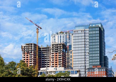 Costruzione moderna di un complesso residenziale con struttura monolitica che utilizza gru a torre in una giornata estiva. Spazio di copia. Foto Stock