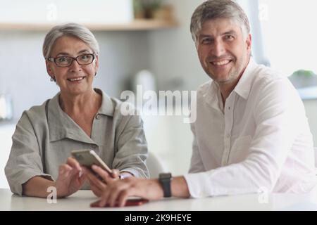 donna d'affari e uomo d'affari sorridenti seduti al tavolo. Foto Stock