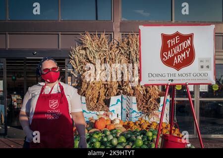 2020 11 07  Tulsa USA Donna Masked raccogliere denaro per l'Esercito della salvezza si trova in piedi da un mucchio di zucche e zucche e paglia ornamentale con segno e bu Foto Stock