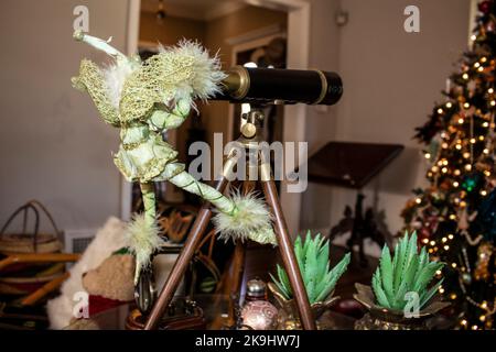 Carino elfo verde figura con ali di lacy coetanei attraverso cannocchiale antico a albero di Natale - fuoco selettivo e bokeh Foto Stock