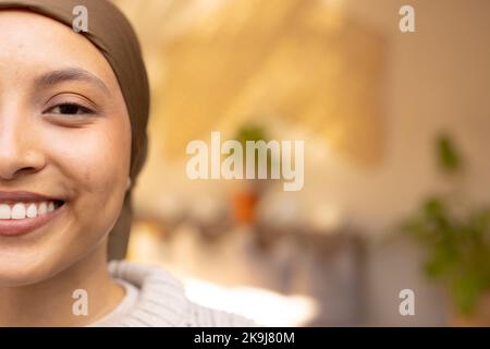 Ritratto di felice donna biraciale indossando hijab, guardando la macchina fotografica e sorridendo Foto Stock