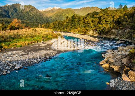 Rapide fluide nel fiume Hokitika vicino al parcheggio Hokitika Gorge sulla costa occidentale dell'isola meridionale, con le alpi meridionali sullo sfondo Foto Stock