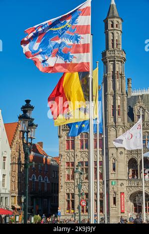 Bandiere che volano nel Markt, Piazza del mercato, Bruges con la bandiera a strisce rosse e bianche di Bruges prominente. Foto Stock