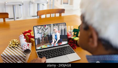 Uomo anziano biraciale che ha la videochiamata di natale con la donna afroamericana Foto Stock