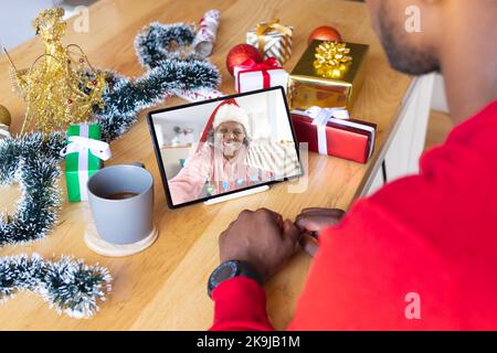 Uomo afroamericano che ha videochiamata di natale con donna afroamericana anziana Foto Stock
