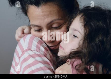 La bambina sconvolta che viene consolata dalla mamma Foto Stock