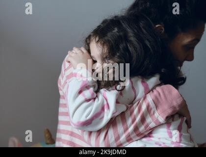 La bambina sconvolta che viene consolata dalla mamma Foto Stock