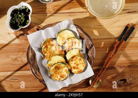 Vista dall'alto Hobak Jeon o Zucchini fritti in padella serviti con salsa di soia, semi di sesamo e Makgeolli Foto Stock