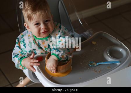 Il bambino che mangia da solo imparando con il metodo dello svezzamento guidato dal bambino Foto Stock