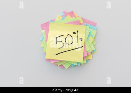 Scritto a mano al 50% su una nota adesiva gialla su sfondo isolato bianco Foto Stock