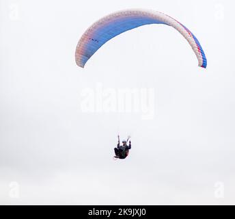 Skydiving sport estremi - paracadutista con paracadute dispiegato. Lo sportivo che vola su un parapendio. Bellissimo parapendio in volo su un dorso leggero Foto Stock