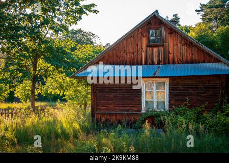 Bellissimo paesaggio rurale. Vecchio cottage in legno con finestra bianca. Sole pomeridiano Foto Stock