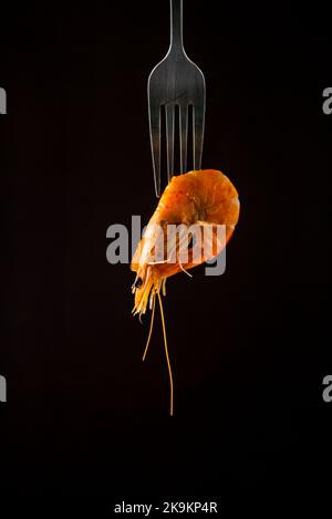 Vapore di gamberetti al vapore sulla forcella superficie di copia isolata in nero. Sfondo nero isolato retroilluminazione concetto di cibo retroilluminato pronto per mangiare Foto Stock