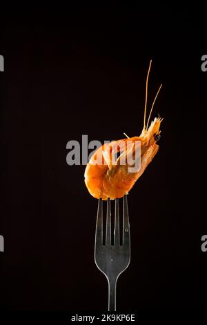 Vapore di gamberetti al vapore sulla forcella superficie di copia isolata in nero. Sfondo nero isolato retroilluminazione concetto di cibo retroilluminato pronto per mangiare Foto Stock