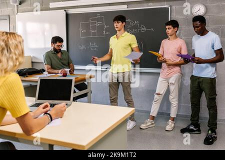 Gruppo di tre giovani studenti maschi che insegnano progetto personale a scuola Foto Stock