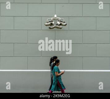 Due persone che camminano sotto telecamere di sorveglianza CCTV a Singapore, Singapore. Foto Stock