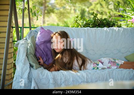 la ragazza si trova sul divano con uno smartphone Foto Stock