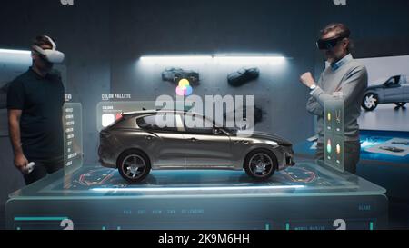 Due ingegneri di sviluppo scelgono un colore per un prototipo di auto elettrica sostenibile e rispettoso dell'ambiente. Utilizzo di cuffie per la realtà virtuale e ologramma. Tecnologia all'avanguardia. Sviluppatori di design per auto. Foto Stock