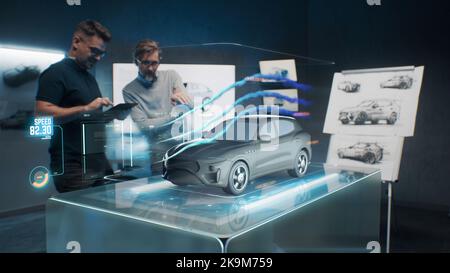 Progettisti di automobili che utilizzano l'app olografica nel tablet digitale. Sviluppare un'auto elettrica moderna e innovativa, all'avanguardia e ecologica, con standard sostenibili. Testano le qualità aerodinamiche Foto Stock