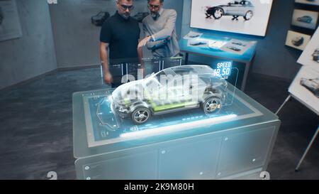 Due ingegneri di sviluppo. Testare le prestazioni di velocità di un'auto elettrica ecologica all'avanguardia con standard sostenibili utilizzando una scrivania per realtà aumentata olografica avanzata. Foto Stock