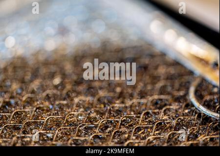 Macro di messa a fuoco selettiva di un filtro sporco cappa gamma cucina intasato di grasso. Foto Stock