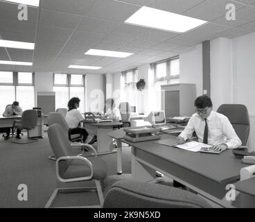 1989, dipendenti storici, di sesso maschile e femminile che lavorano alle loro scrivanie in un ufficio a pianta aperta, Inghilterra, Regno Unito. Nella foto si possono vedere i personal computer dell'epoca Foto Stock