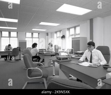 1989, dipendenti storici, di sesso maschile e femminile che lavorano alle loro scrivanie in un ufficio a pianta aperta, Inghilterra, Regno Unito. Nella foto si possono vedere i personal computer dell'epoca Foto Stock