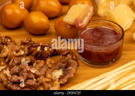Varie varietà di formaggi, noccioli, uova di quaglia affumicate e miele in un vaso di vetro su una superficie di legno. Foto Stock