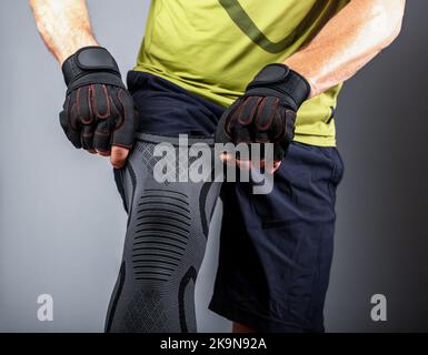Abbigliamento sportivo, sostegno al ginocchio, bendaggio elastico per la compressione, protezione durante l'allenamento in palestra. Foto di alta qualità Foto Stock