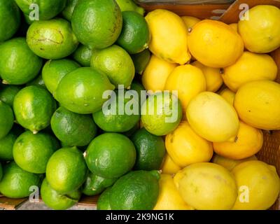 Limoni e lime in una scatola. Sfondo da agrumi diversi. Frutti gialli e verdi. Vitamine. Citrus concept. Nel mercato orientale Foto Stock