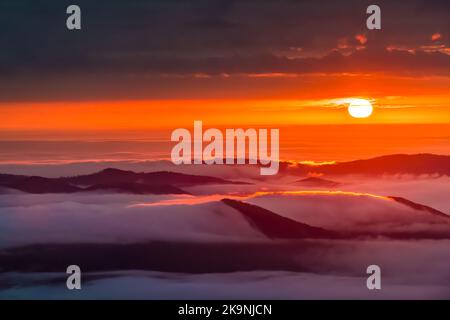 Inversione delle nuvole al sorgere del sole alba mattina a Wintergreen Resort, Virginia località sciistica con colorato sole rosso che sorge sopra l'orizzonte con la nebbia solare Foto Stock