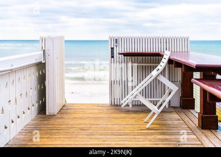 Seaside, Florida, con un padiglione in legno bianco sul lungomare con vista sulle onde dell'oceano del Golfo del Messico e sulle sedie del ristorante e dei cafè, tavoli accanto a recinzioni Foto Stock