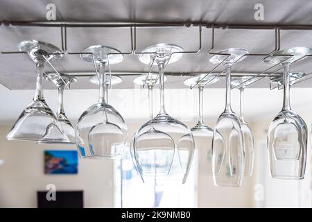 Primo piano del design moderno degli interni della cucina con appesi a testa in giù porta bicchieri da vino vuoto in camera per il deposito Foto Stock