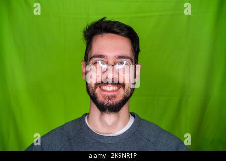 Giovane uomo con abiti casual, che esprime emozioni, che si posa su sfondo verde Foto Stock