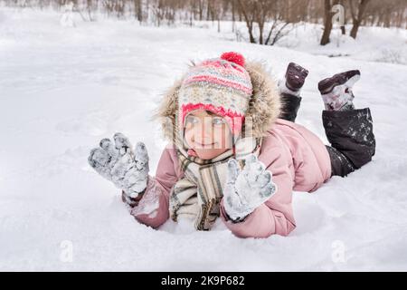 Carina bambina si trova in una nevicata all'aperto in inverno Foto Stock