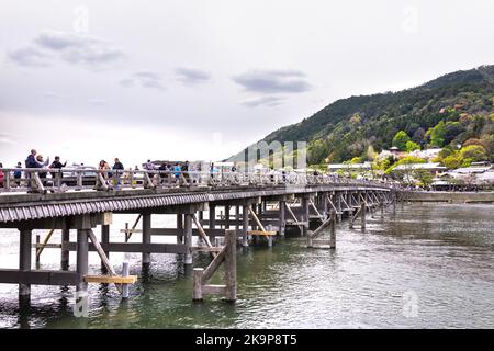 Kyoto, Giappone - 11 aprile 2019: Ponte in legno di Togetsu-kyo con persone che scattano foto del fiume Katsura con le montagne del parco Arashiyama in primavera Foto Stock