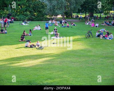 Vienna, Austria - Giugno 2022: Persone, turisti e locali rilassarsi e divertirsi sull'erba verde nel parco Burggarten di Vienna. Foto Stock