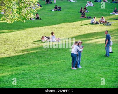 Vienna, Austria - Giugno 2022: Persone, turisti e locali rilassarsi e divertirsi sull'erba verde nel parco Burggarten di Vienna. Foto Stock