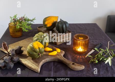 Zucche piccole naturali, candele arancioni su un tavolo bianco, decorazioni di Halloween. Foto Stock