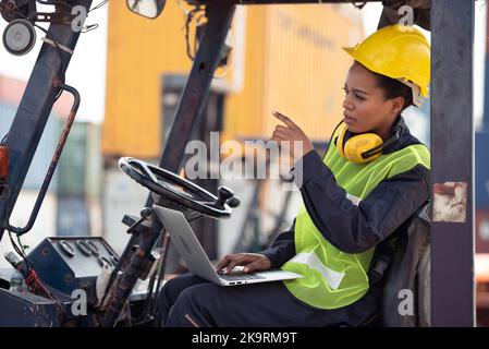 Lavoratrice che guida il carrello elevatore in un magazzino di container industriale. Foto Stock