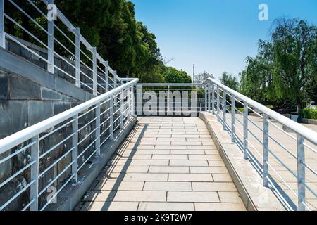 Una rampa per sedie a rotelle, un piano inclinato installato in aggiunta o al posto delle scale, passerella Slope per disabili, persone che spingono passeggini, carrelli Foto Stock