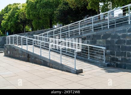 Una rampa per sedie a rotelle, un piano inclinato installato in aggiunta o al posto delle scale, passerella Slope per disabili, persone che spingono passeggini, carrelli Foto Stock