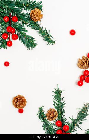 Concetto di Natale, rami di abete che decorano con coni di pino e bacche rosse su sfondo bianco. Foto Stock