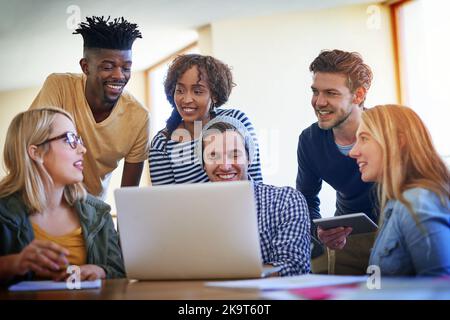 Si è riunito per una sessione di studio di gruppo. Un gruppo di studenti universitari che lavorano insieme su un computer portatile nella biblioteca del campus. Foto Stock